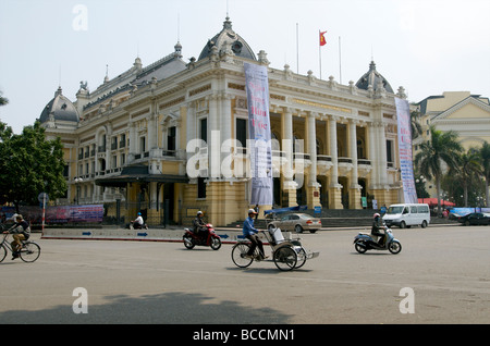 A cyclo driver peddles past the Opera House in Hanoi Vietnam Stock Photo