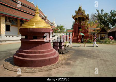 Thai visitors walk through the grounds of Lamphun's Wat Phra That Haripunjaya Buddhist temple Stock Photo