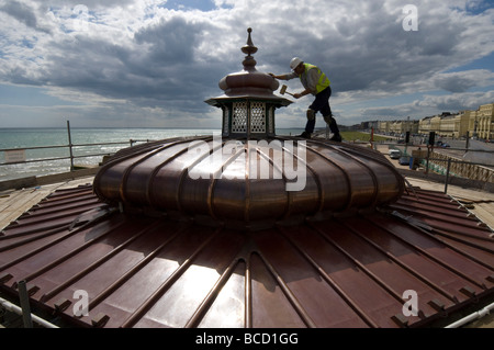 A workman hammering a new copper roof onto a Victorian bandstand on Brighton and Hove seafront Stock Photo