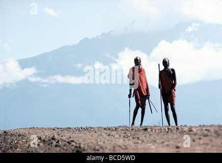 Two Maasai warriors or moran silhouetted against Mount Mawenzi Klimanjaro seen from Loitokitok near Amboseli Kenya East Africa Stock Photo