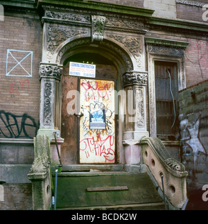 A door boarded up with graffiti on a derelict brownstone house in a Harlem neighborhood New York City, USA      KATHY DEWITT