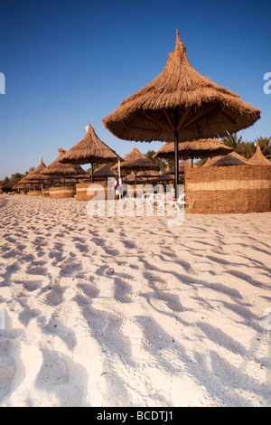 Thatched beach umbrellas and windbreaks on a deserted beach Stock Photo