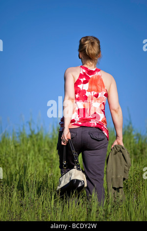 Rear view of woman walking in tall grass, Manitoba, Canada. Stock Photo