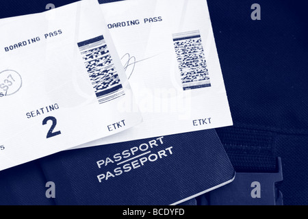 Two Boarding Passes and Canadian Passports with luggage in the background, blue tone Stock Photo