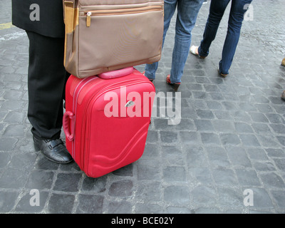 businessman with luggage standing in street in city town Stock Photo