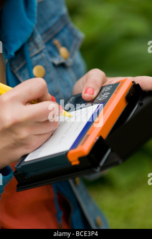 A freelance self employed female production assistant on a television shoot making notes of the content of a video tape label Stock Photo
