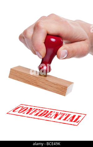 Hand holding a rubber stamp with the word Confidential Stock Photo