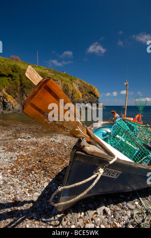 Small fishing boat and oars on the beach at Cadgwith Cove on a bright Summer day on the Cornish coast Cornwall UK Stock Photo