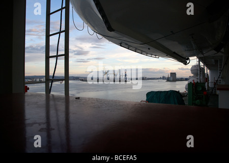 looking out under lifeboats on the side of a passenger ferry towards belfast port in the uk Stock Photo