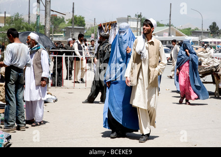 A Muslim man and woman in a burqa and thawb watch the sunset as a Dhow ...