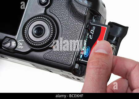 Male hand pushing a Sandisk two gigabyte 2gb compact flash memory card into a digital SLR camera Stock Photo