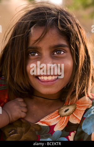 Young Smiling Indian Girl with Colourful Flowery dress, Thar Desert, Near Jaisalmer, Rajasthan State, India. Stock Photo