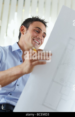 male architect looking at blueprint and smiling Stock Photo