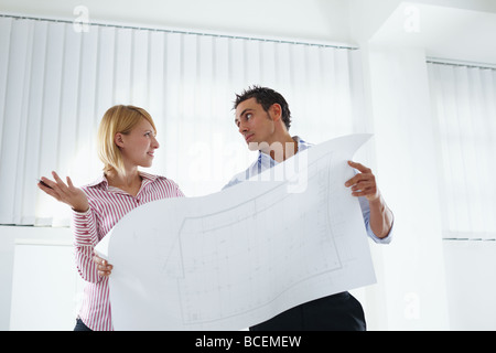 female and male architects holding blueprint Stock Photo