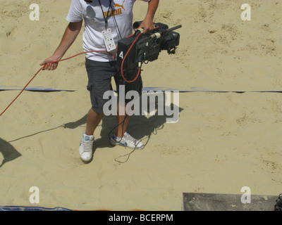 man with tv camera filming at beach event Stock Photo