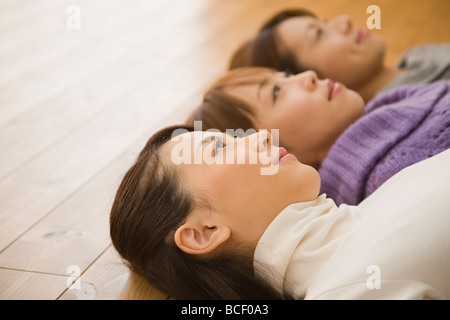 Three young women lying on floor Stock Photo