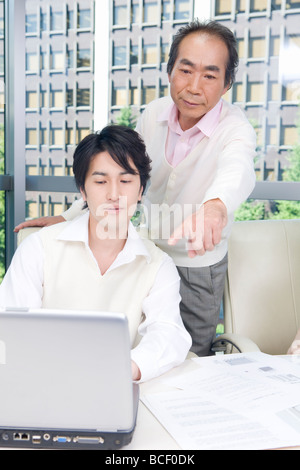Mature man and mid adult man working in office Stock Photo