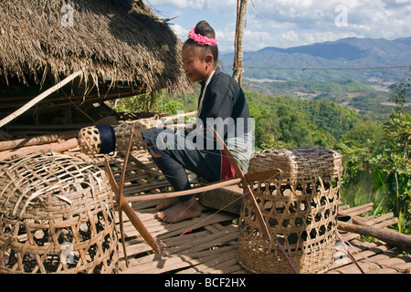 Myanmar, Burma, Pan-lo. A woman of the small Ann tribe spools cotton thread for weaving on the bamboo platform of her home. Stock Photo