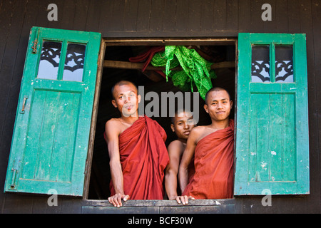 Myanmar, Burma, Rakhine State, Sittwe. Three novice monks look out of their dormitory window at the Pathain Monastery. Stock Photo