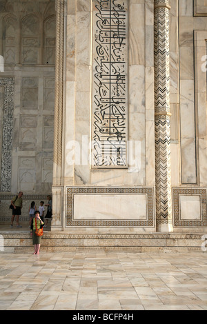 Detail of the scripts inlaid into the white marble around the Taj Mahal Agra with tourists included for scale Stock Photo