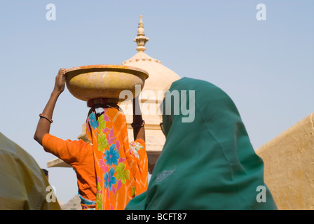 Indian woman walks holding heavily loaded basket on her head. Stock Photo