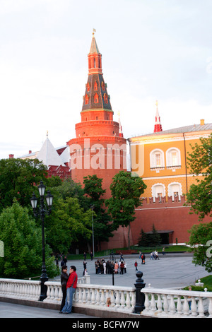 A young couple dates by the walls of Kremlin in Moscow next to the Arsenal tower, one of 20 towers of Moscow Kremlin seen behind them. Stock Photo