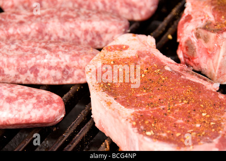 Raw steaks and bratwurst on a barbecue grill ready to be cooked Stock Photo