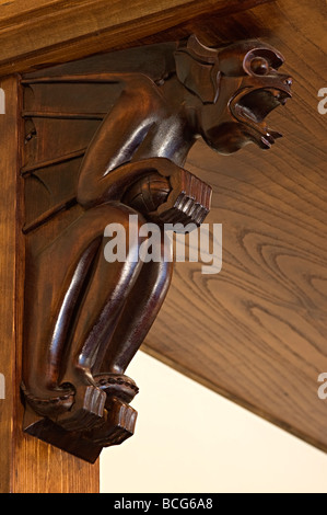 carved wooden supports in a pub on shelves carved and shaped like gargoyles as pub decoration Stock Photo