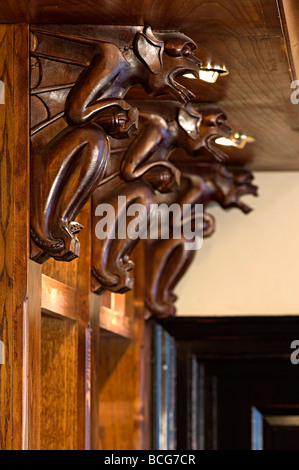 carved wooden supports in a pub on shelves carved and shaped like gargoyles as pub decoration Stock Photo