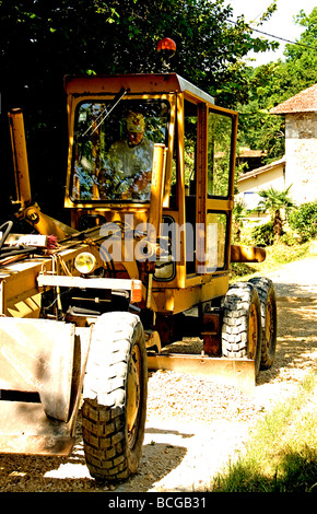 Road grader at work on a small country road in France Stock Photo