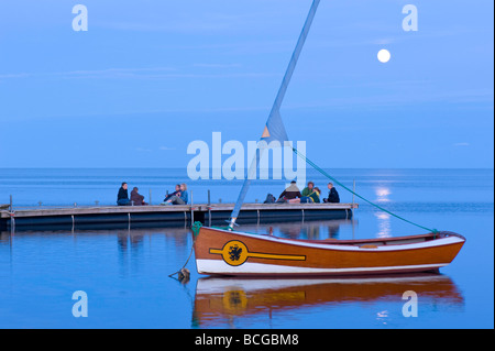 People relax on wooden pier overlooking Puck Bay early evening Hel Peninsula Baltic Sea Poland Stock Photo