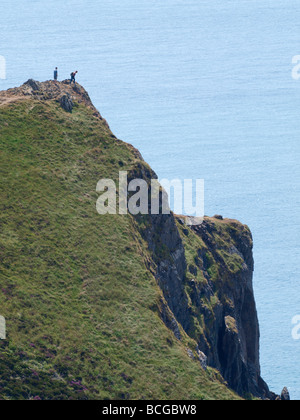 Walkers looking over the cliff edge at the end of the path on the coastal path near crosstown, North Cornwall. Stock Photo