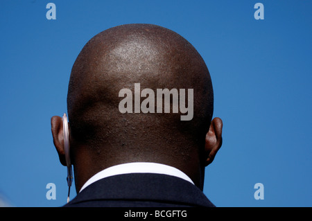 Back of the bald head of a black security guard against a clear blue sky Stock Photo