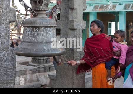 Kathmandu, Nepal. Nepali Worshipper with Child Rings a Bell at Swayambhunath Temple. Bells drive evil spirits away. Stock Photo