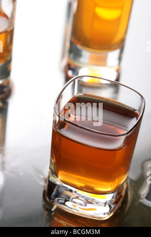 A shot glass full of whiskey with other shot glasses in the background Shallow DOF Stock Photo