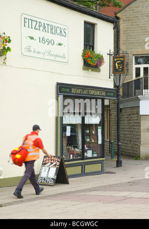 Postman walking past Fitzpatrick's Herbal Health temperance bar, Rawtenstall, Lancashire, England UK Stock Photo