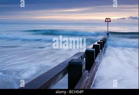 Dawn breaking over wooden groyne at Swanage on the Dorset Purbeck coast South West England UK Stock Photo