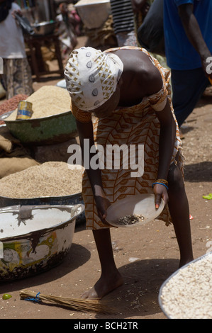 young girls sorting through dirt on market floor for rice grains in Ghana Stock Photo