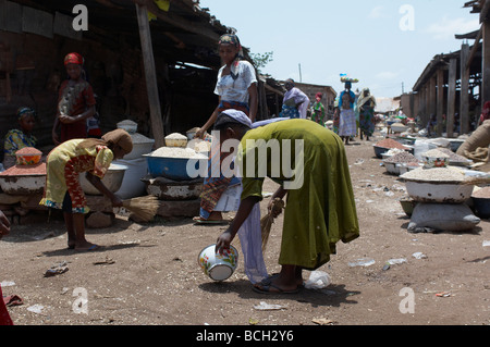 young girls sorting through dirt on market floor for rice grains in Ghana Stock Photo