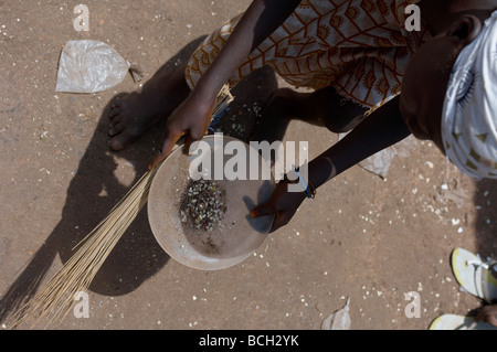 young girls sorting through dirt on market floor for rice grains in Ghana Stock Photo