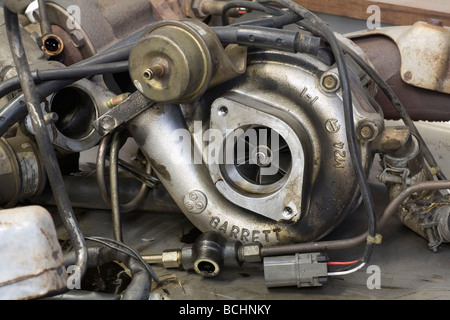 broken turbocharger sitting on a workbench in a car garage Stock Photo