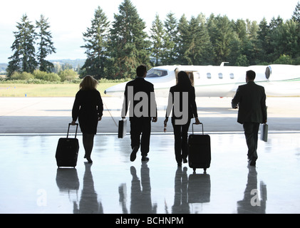 Group of businesspeople walking to corporate jet Stock Photo