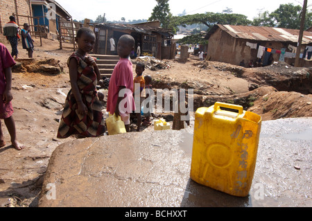 Children collecting  water from contaminated spring. Kamwockya Kampala Uganda Stock Photo
