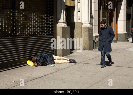 Homeless man sprawled out on 5th Avenue in New York City Stock Photo