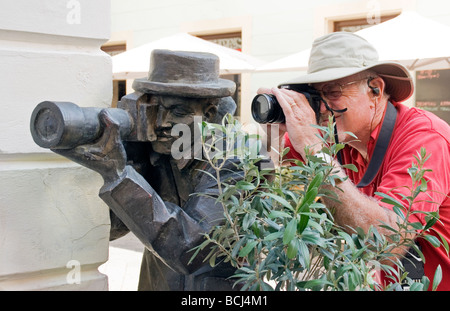 Bratislava tourist-photographer taking aim with public statue, The Paparazzo, in Old Town Stock Photo