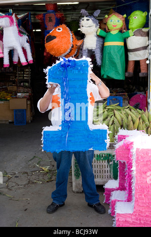 Person at shop holding �辱ñ���ٲ� in the shape of the numeral 1 obscuring his face Stock Photo