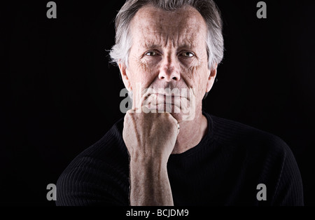 Striking Shot of a Senior Man Resting his Head on Chin Stock Photo