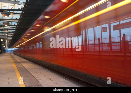 Red subway train speeding through a subway station Stock Photo