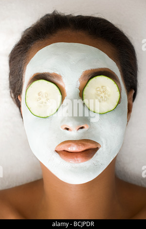 Woman wearing face mask and cucumber