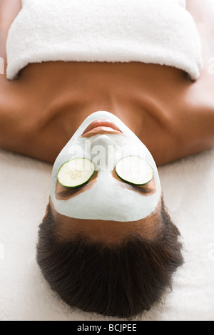 Woman wearing face mask and cucumber
